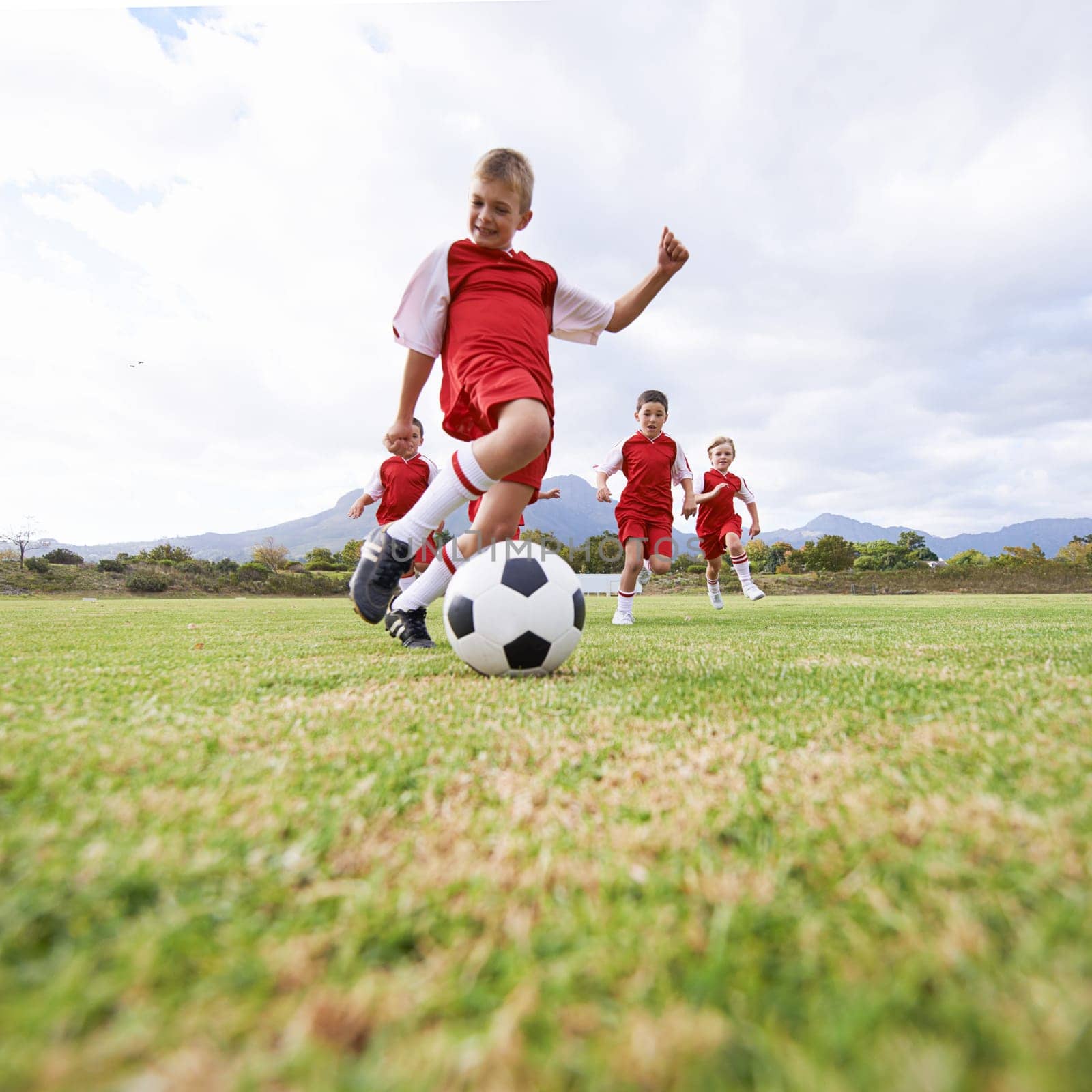 Hes ahead of the pack. a childrens soccer team on the field. by YuriArcurs