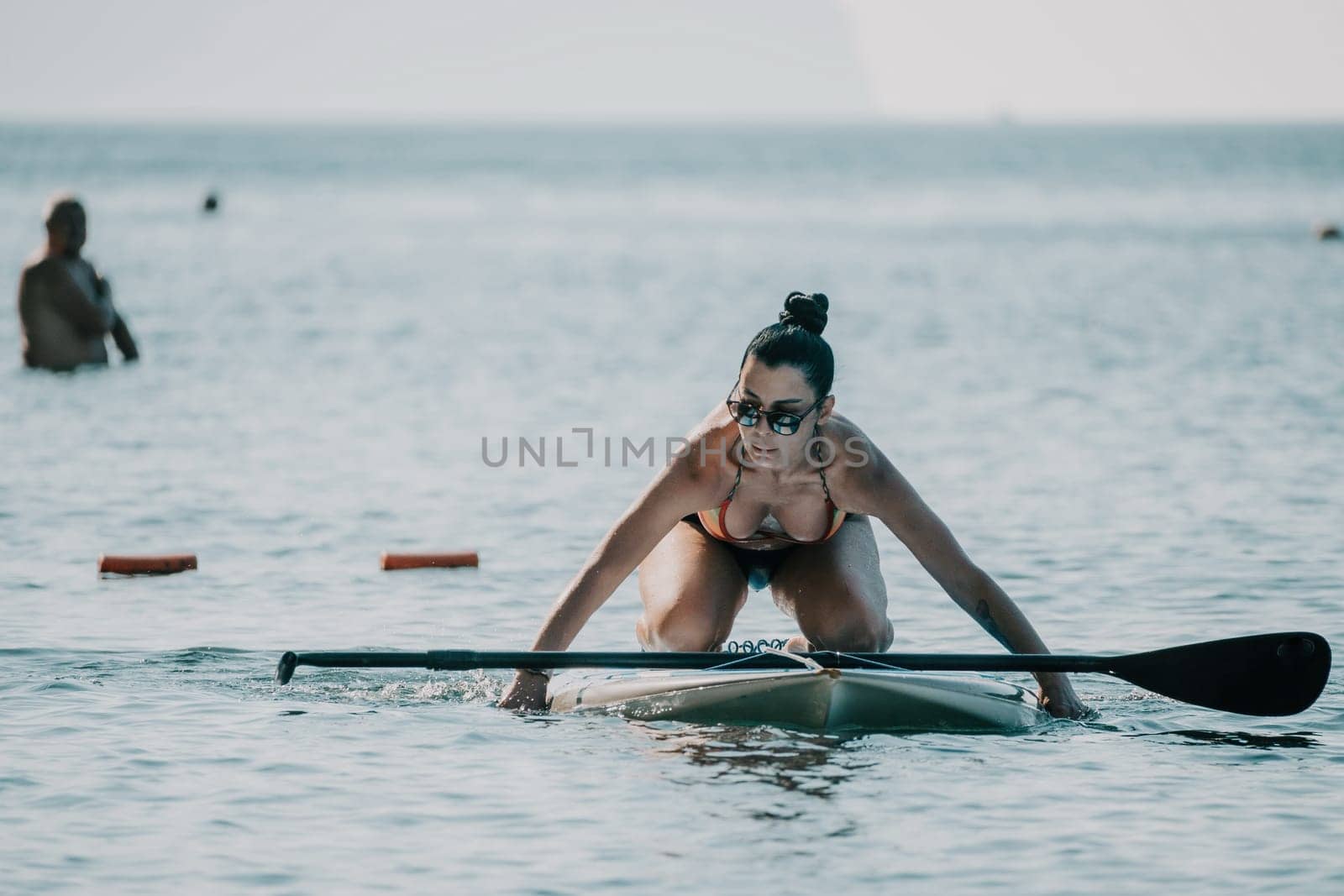 Sea woman sup. Silhouette of happy middle aged woman in rainbow bikini, surfing on SUP board, confident paddling through water surface. Idyllic sunset. Active lifestyle at sea or river