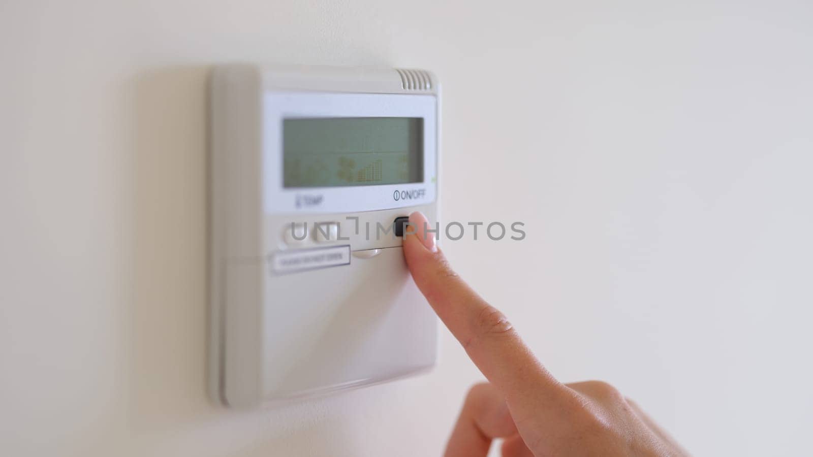 Female finger pressing air conditioner button on wall closeup. Household appliances for home convenient control concept