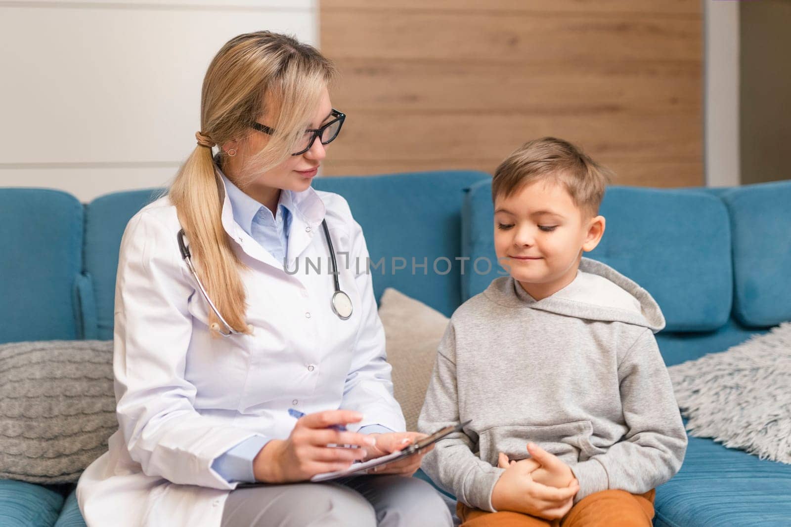 A family doctor examines a little boy at home. Pediatrician girl treats a child.