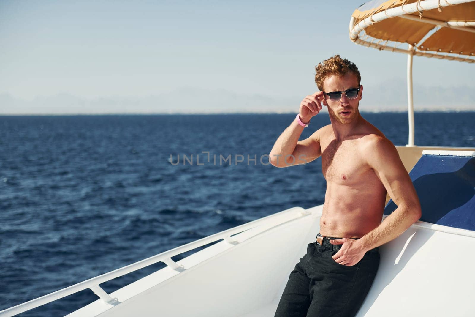 In sunglasses. Young male tourist is on the yacht on the sea. Conception of vacation.