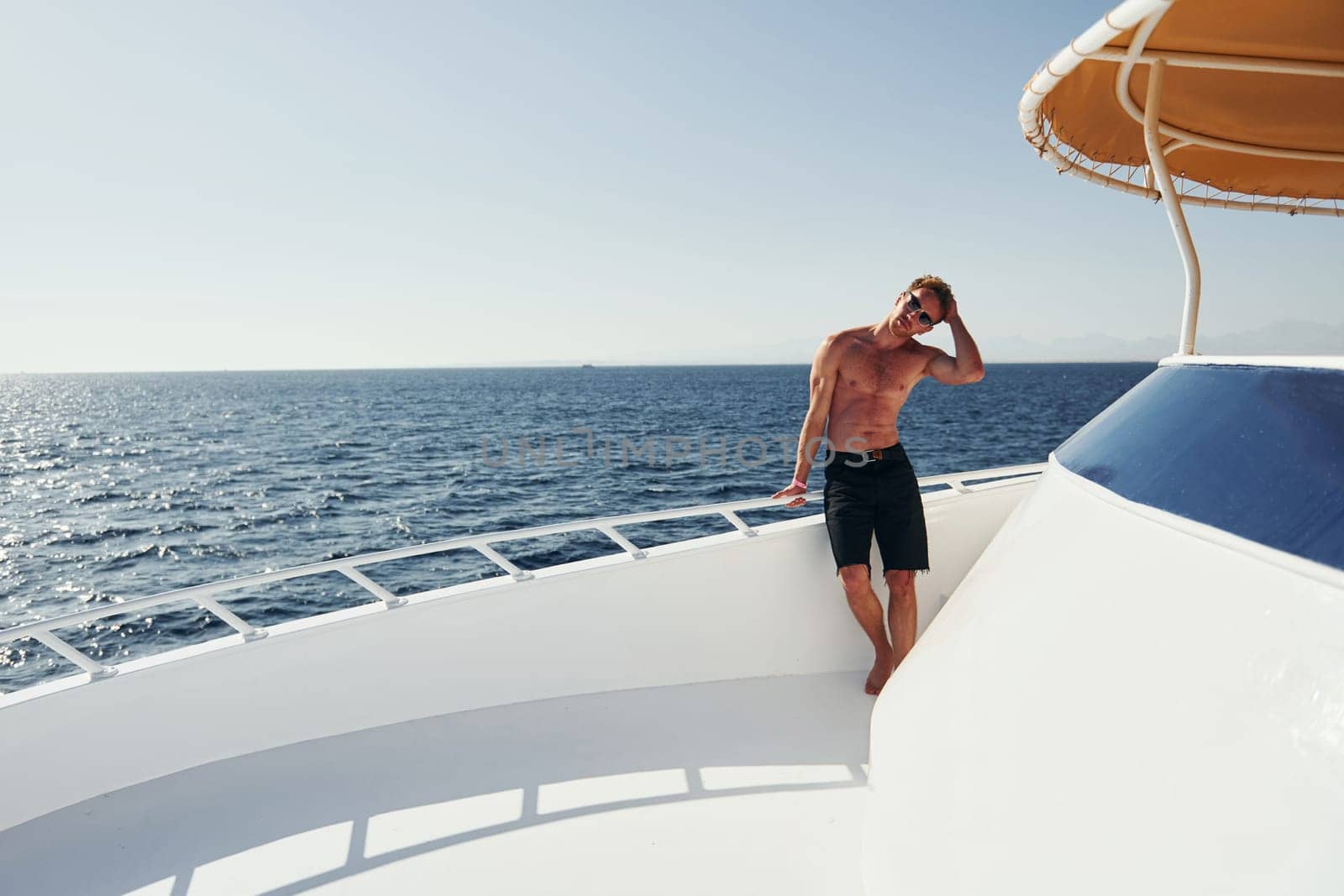 In sunglasses. Young male tourist is on the yacht on the sea. Conception of vacation.