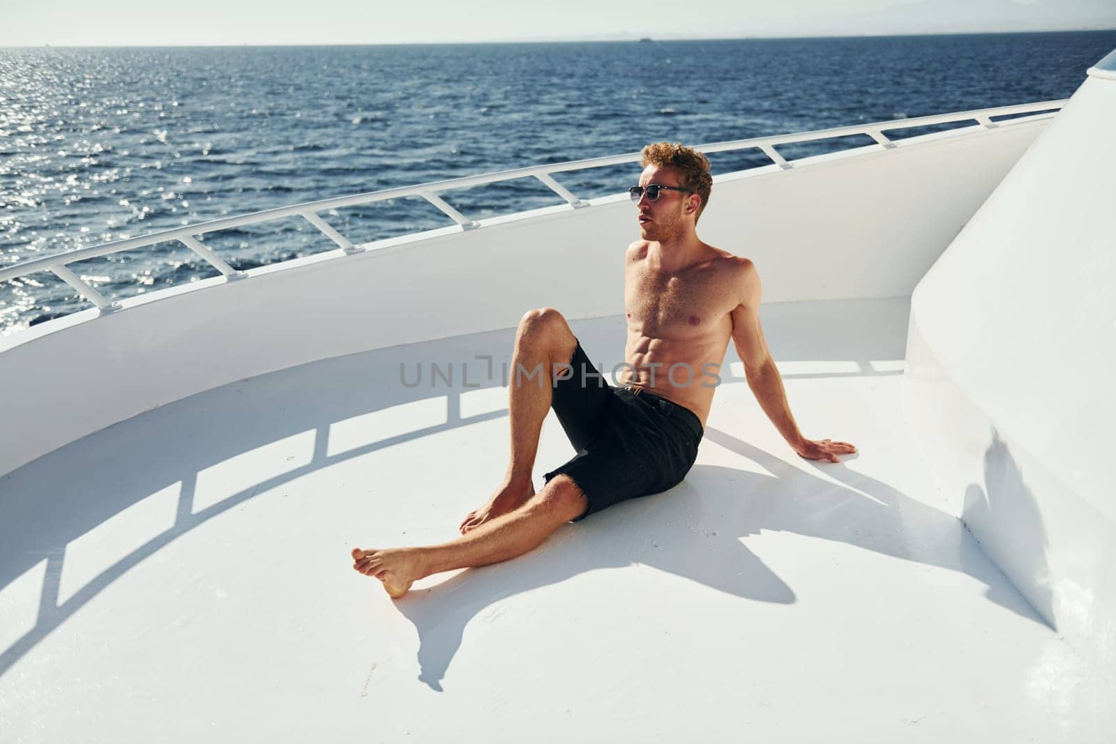 In sunglasses. Young male tourist is on the yacht on the sea. Conception of vacation.