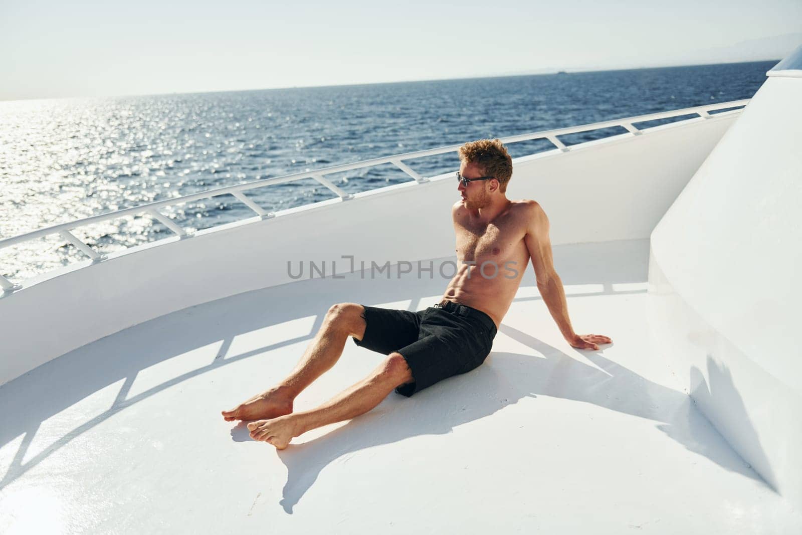 In sunglasses. Young male tourist is on the yacht on the sea. Conception of vacation.