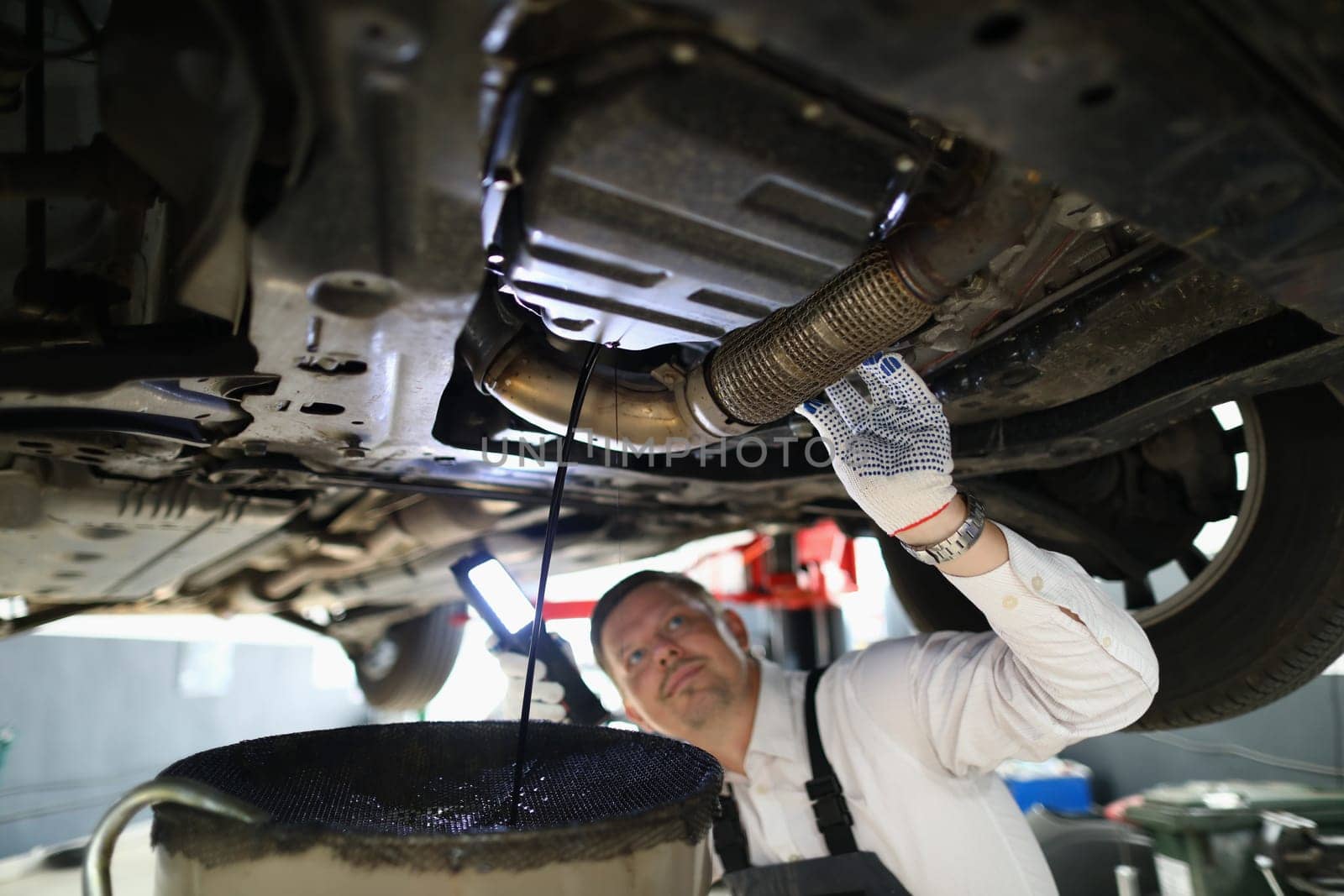 Auto mechanic repairman inspecting car engine in garage of service station by kuprevich