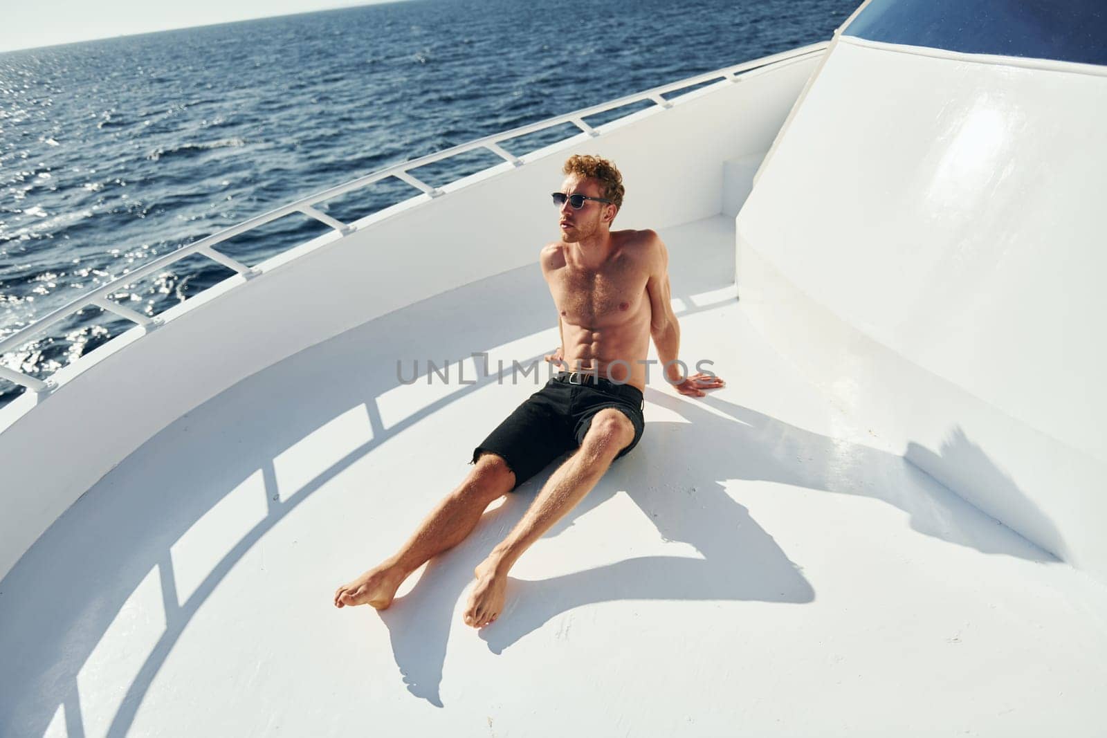 In sunglasses. Young male tourist is on the yacht on the sea. Conception of vacation by Standret