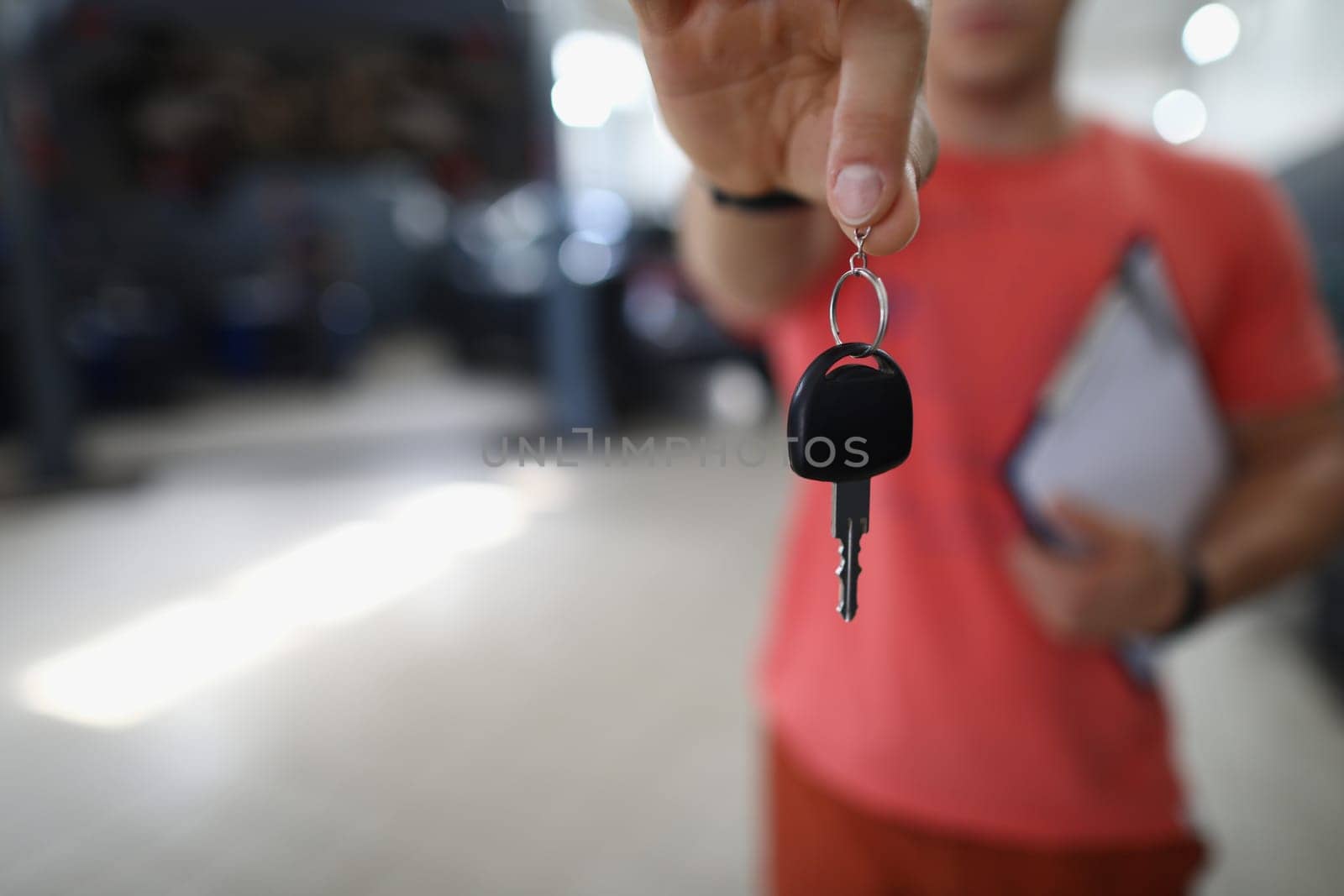 Person mechanic handing over key to car in workshop. Guarantee of quality auto repair concept