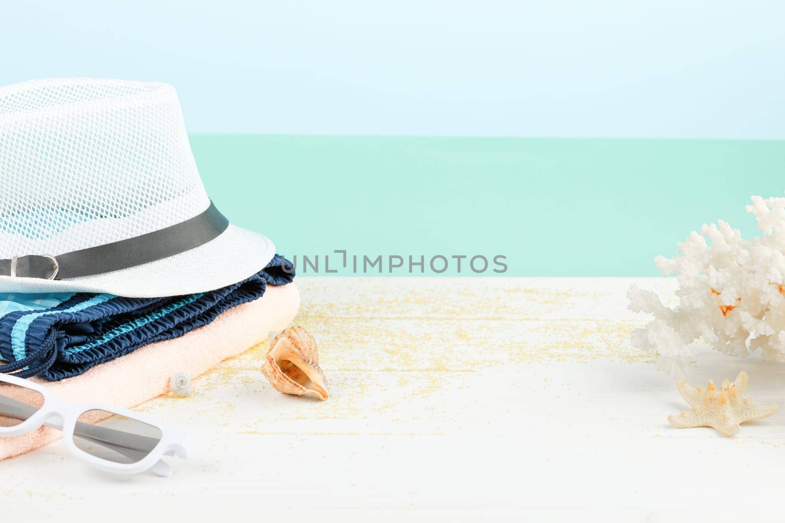 Beach hat with sunglasses and shorts on white wooden background. Summer vacation concept. Starfish and seashells.