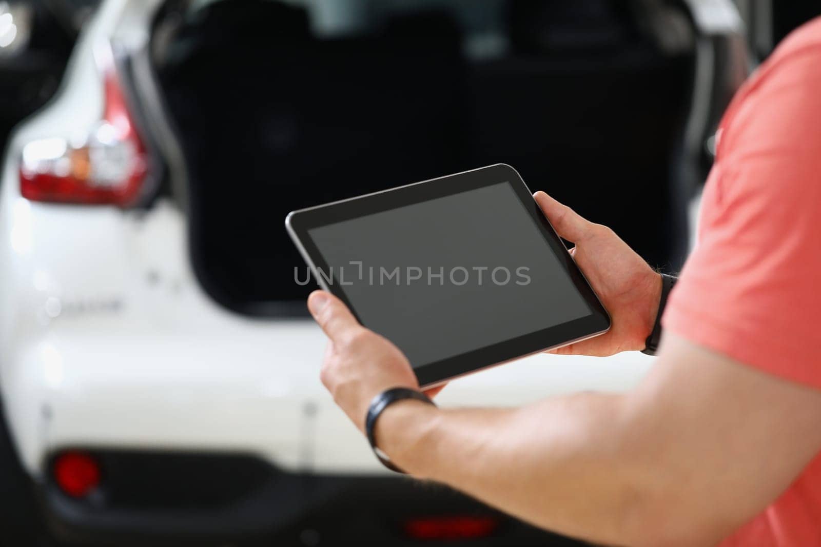 Rear view of worker holding tablet and checking machine. Auto mechanic with tablet and applications for car health diagnostics