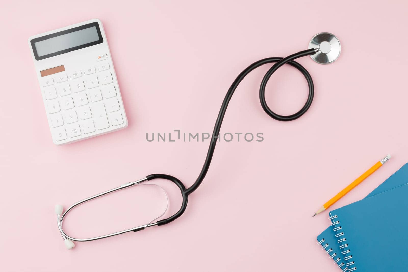 Stethoscope with notepad on pink background. Health insurance concept. Spiral notebook and pencil. Flat lay