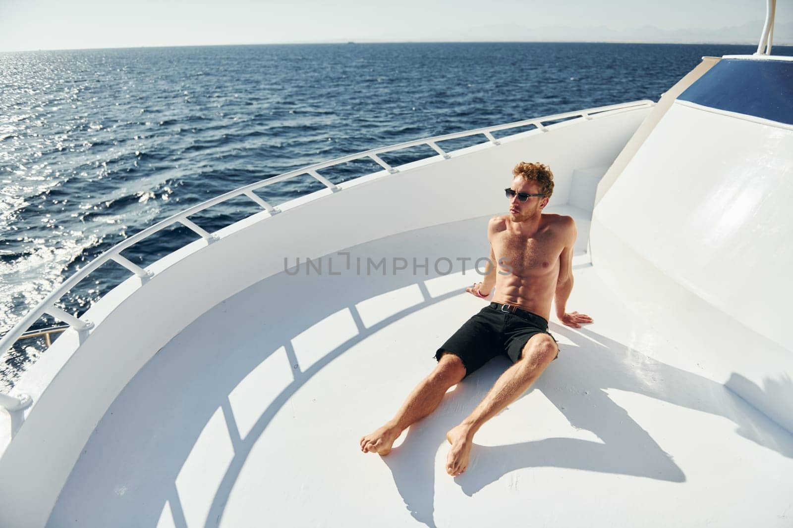Warm weather. Young male tourist is on the yacht on the sea. Conception of vacation by Standret