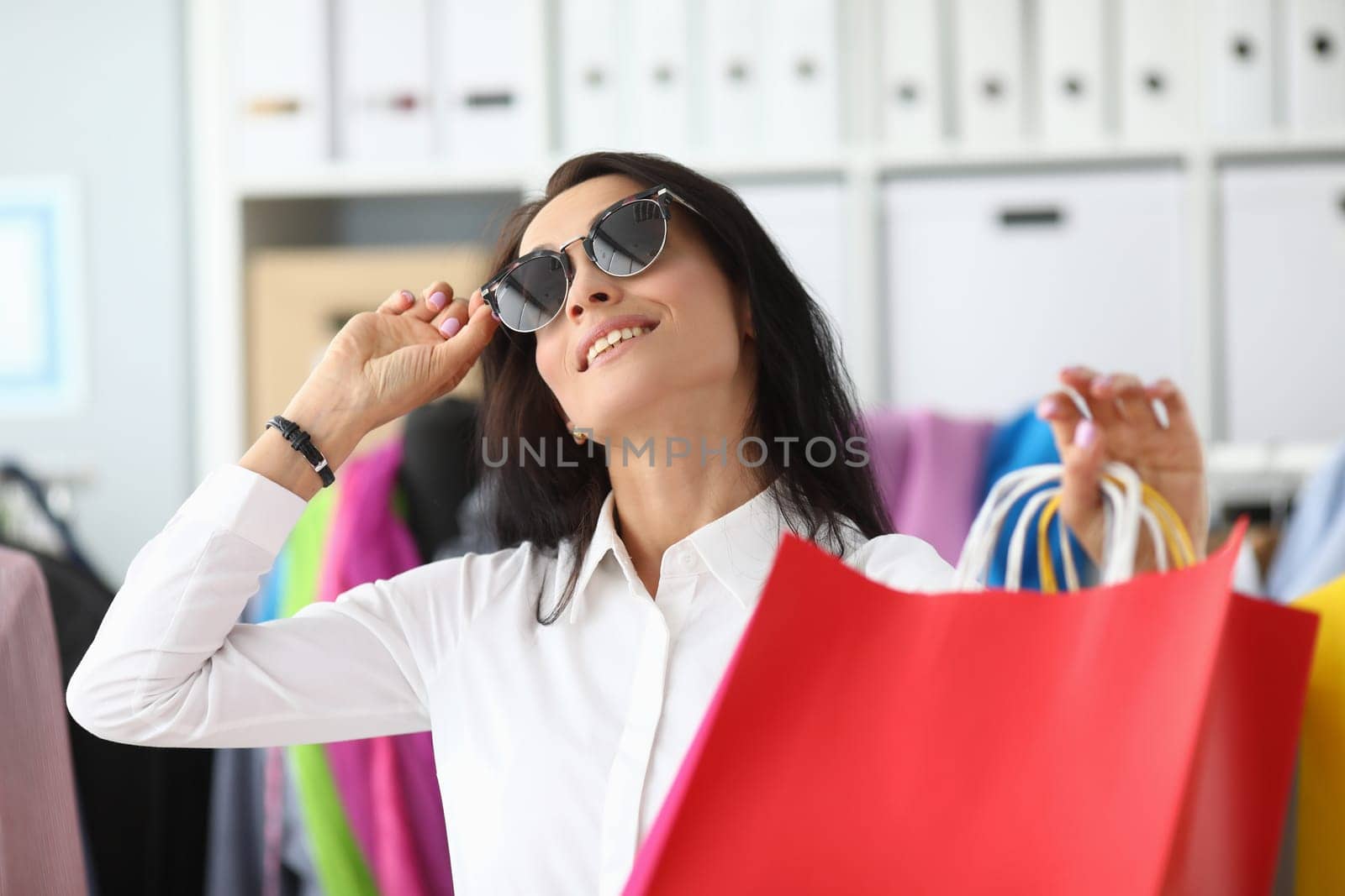 Smiling woman in sunglasses with shopping bags by kuprevich