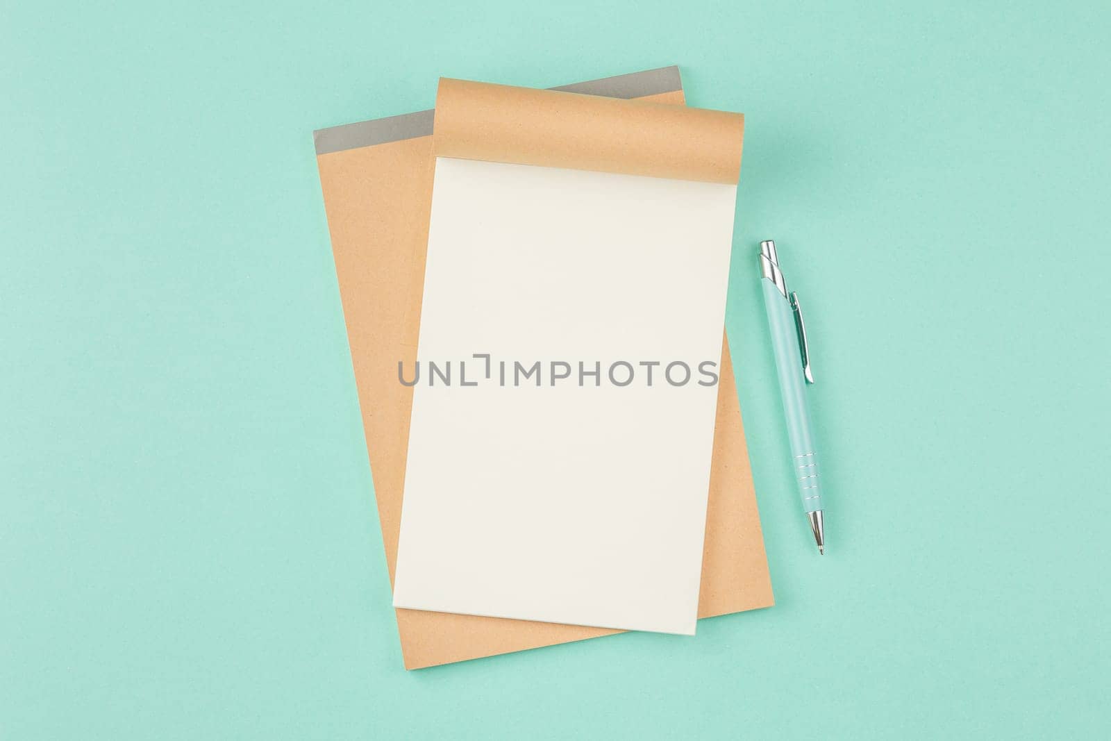 Open school notebook with pen on isolated cyan background. Open craft album. Top view.