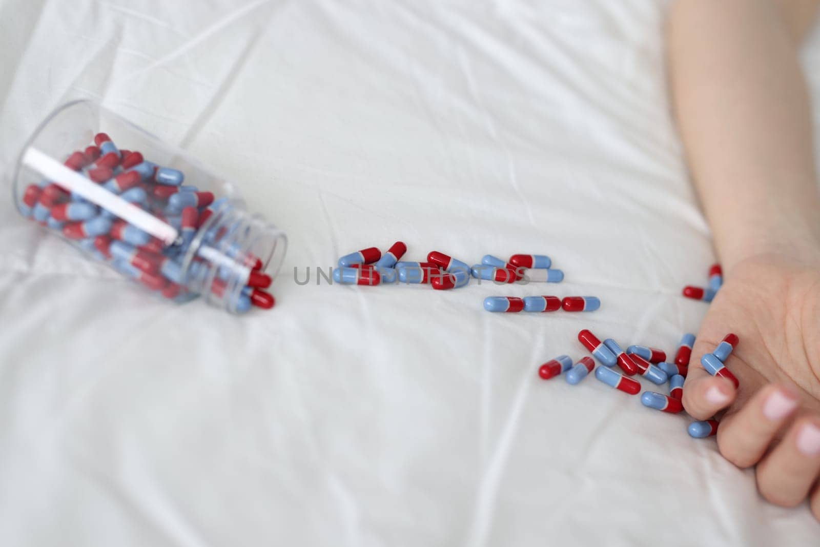Closeup of woman hand and tablet on bed. Suicide due to drug overdose concept