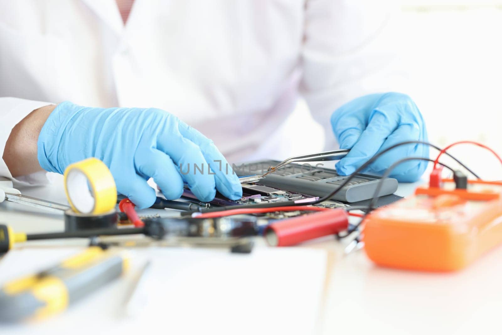 Technician repairs motherboard of smartphone in laboratory by kuprevich