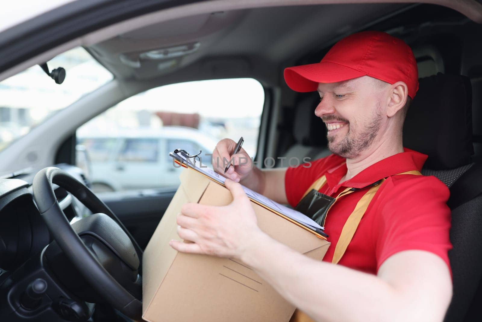 Happy delivery man with cardboard box checklist in van. Delivery man sitting in van and checking the delivery list concept