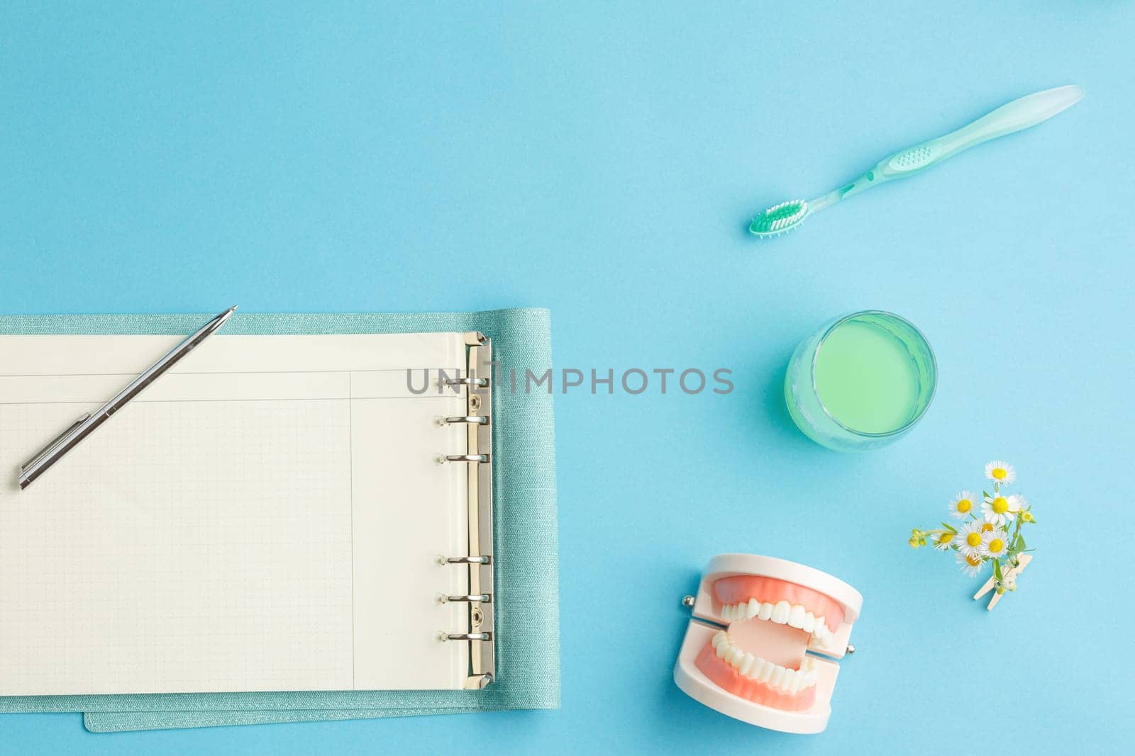 Dentist table top view. Dentures and hygiene products. Notepad with a pencil on a blue background. Flat lay.
