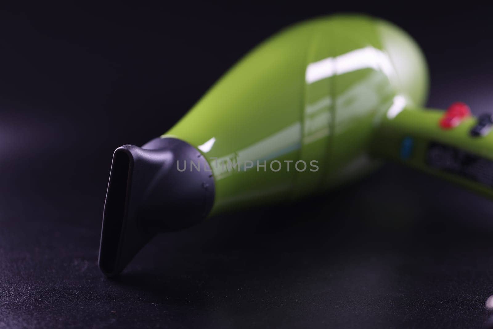 Professional hair dryer of bright green color on gray background closeup. Styling and drying women and men hair