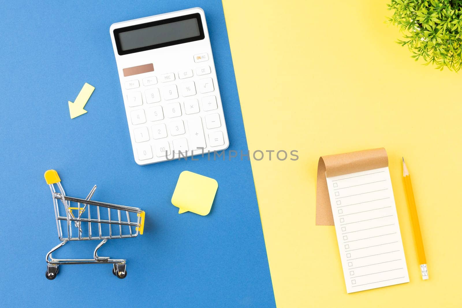 Supermarket trolley with calculator and shopping list. Discounts and promotions concept. Flat lay.