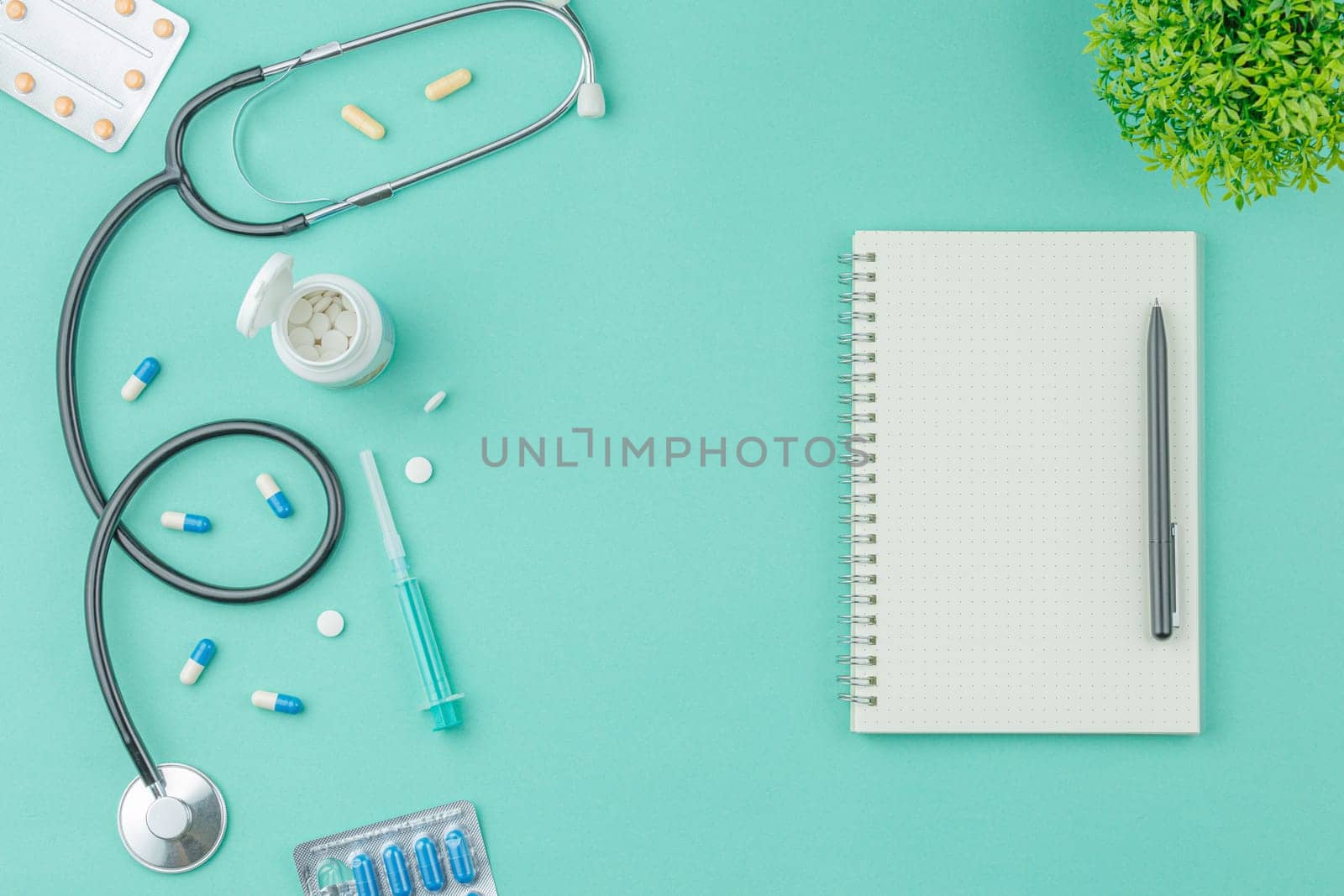 Medical equipment with stethoscope and spiral notebook in doctor office on green desk background top view. Nurse desktop concept.
