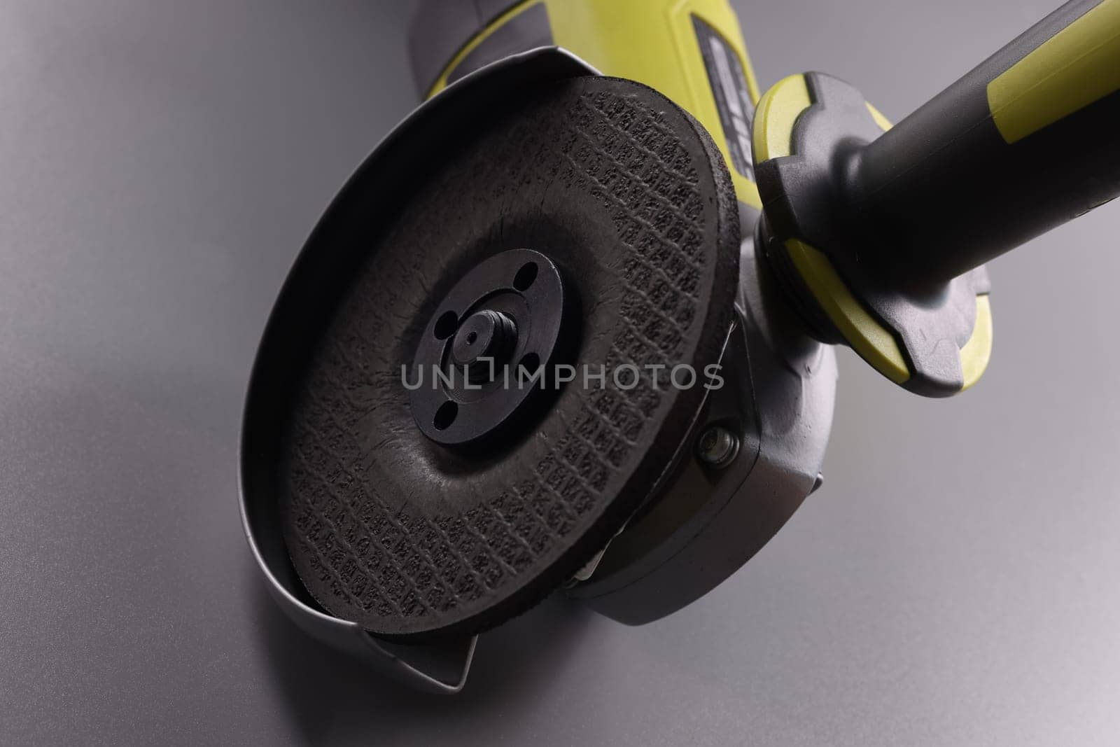 Powerful angle grinder with abrasive disc on gray background. Construction tool concept