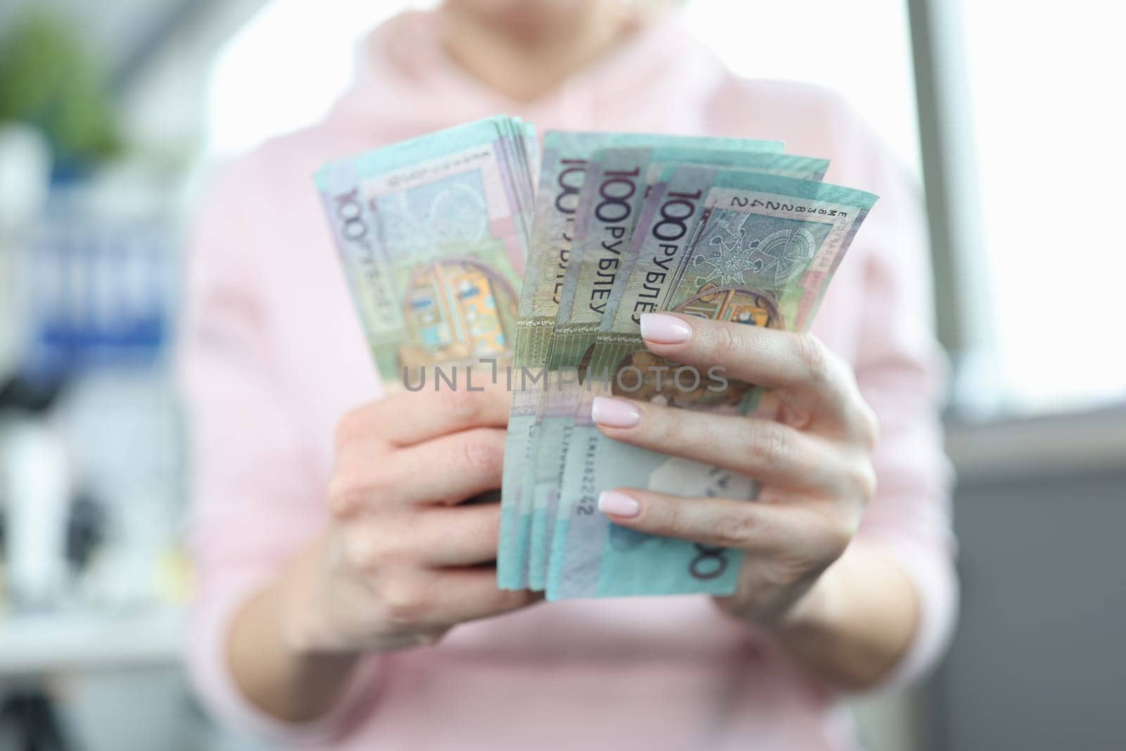 Women hands hold one hundred ruble Belarusian banknotes. Ruble inflation and rising prices in Belarus concept