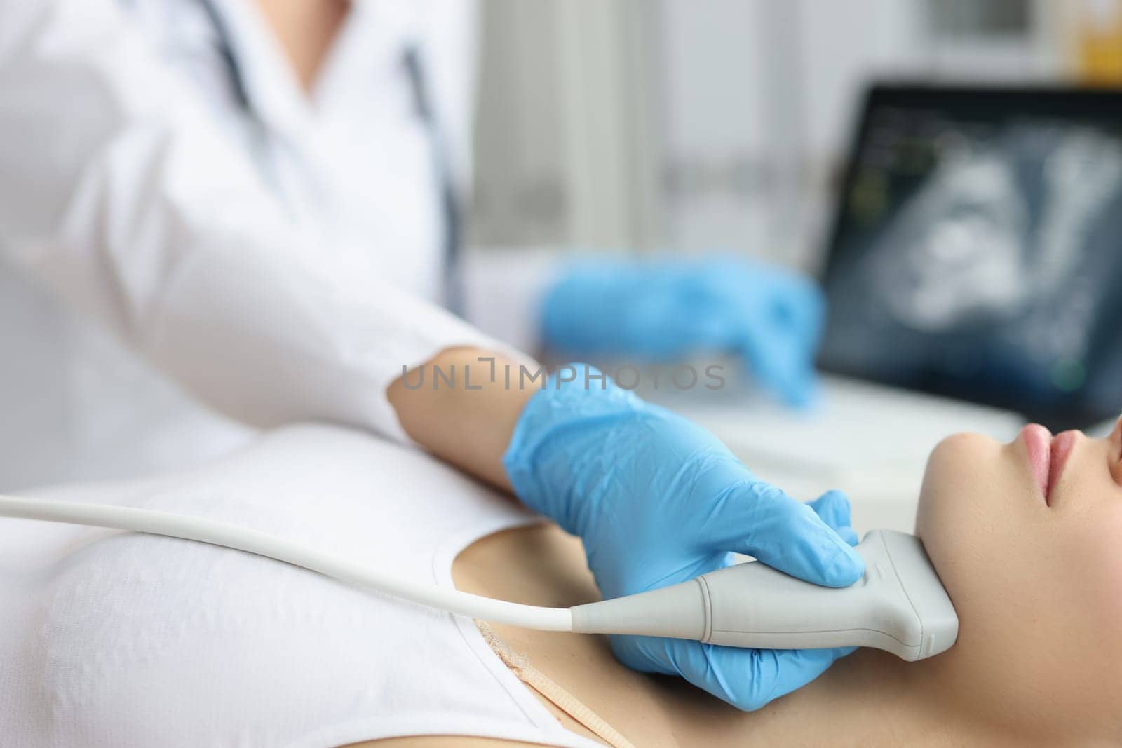 Doctor examining thyroid of female patient with ultrasound scan in clinic. Ultrasound of maxillofacial area concept