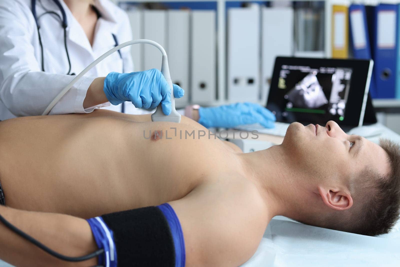 Doctor places ultrasound probe on chest of male patient by kuprevich