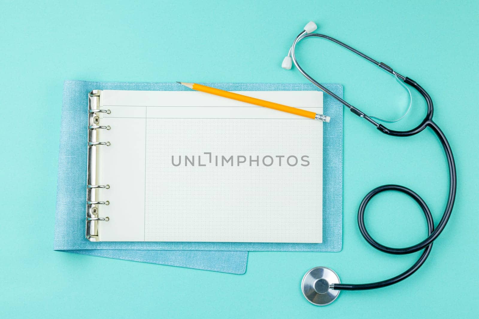 Stethoscope with notepad on green background. by alexxndr