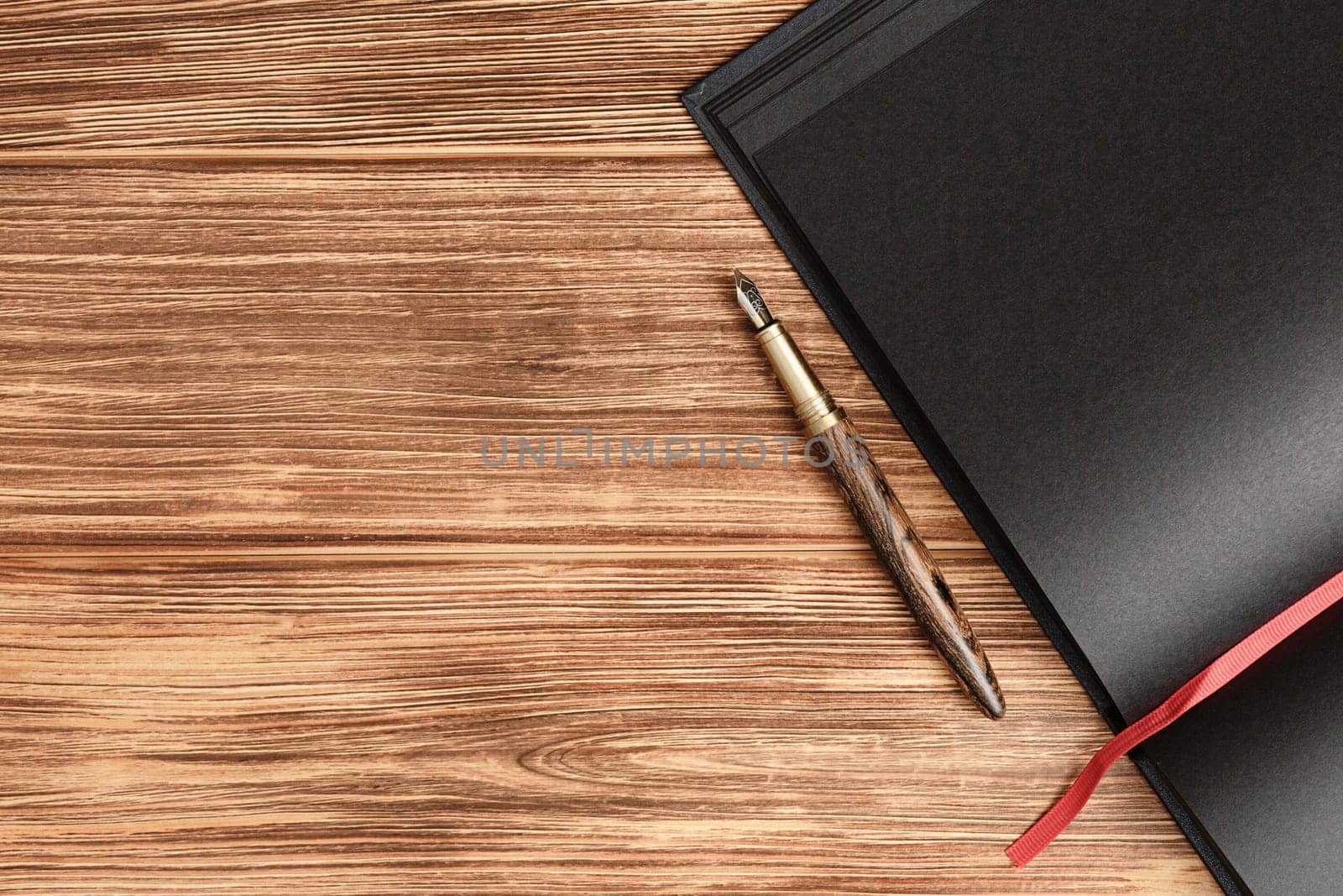 Black notepad fountain pen on a wooden background by alexxndr