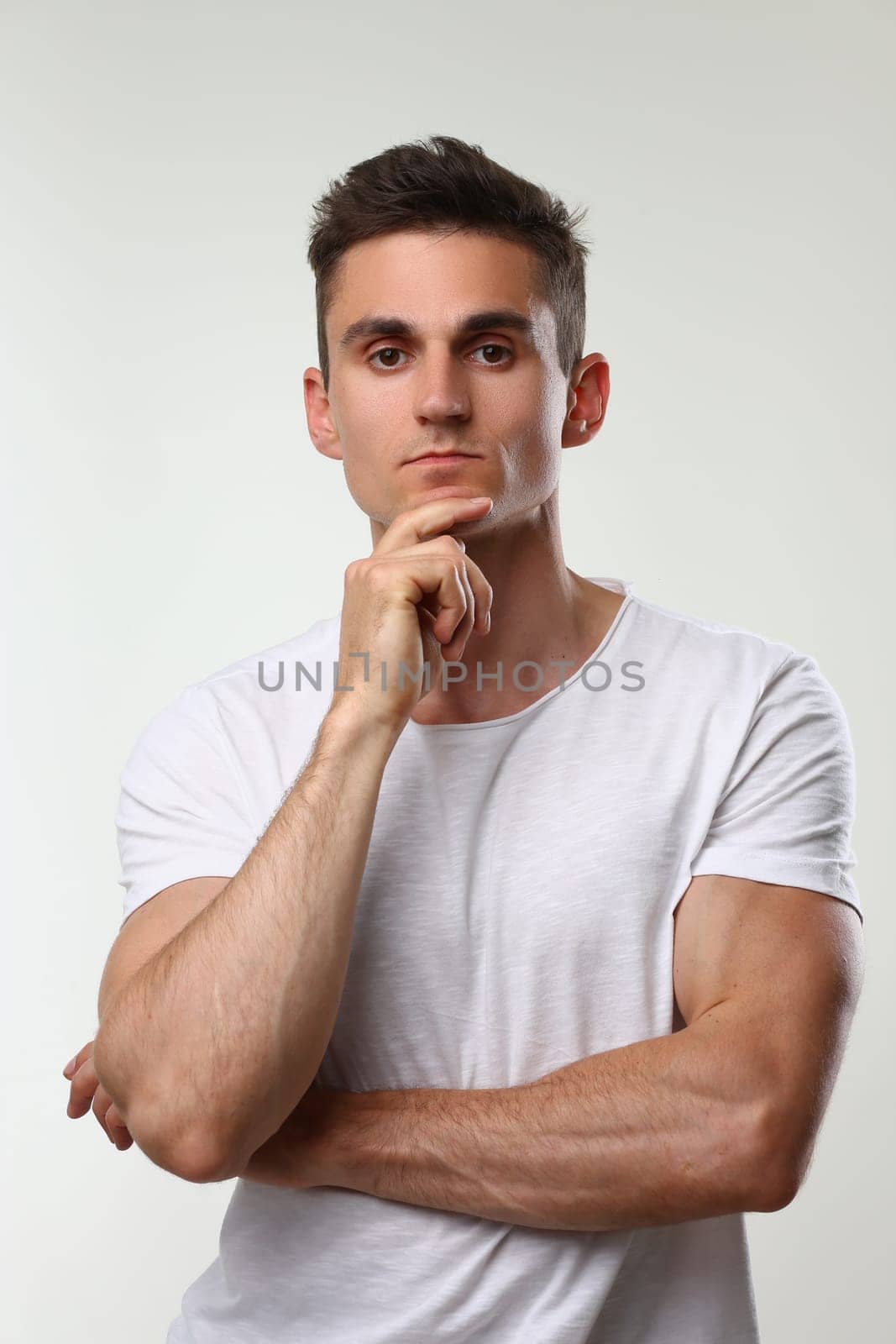 Portrait of young handsome athletic man in white t-shirt. Male brutality and masculinity concept