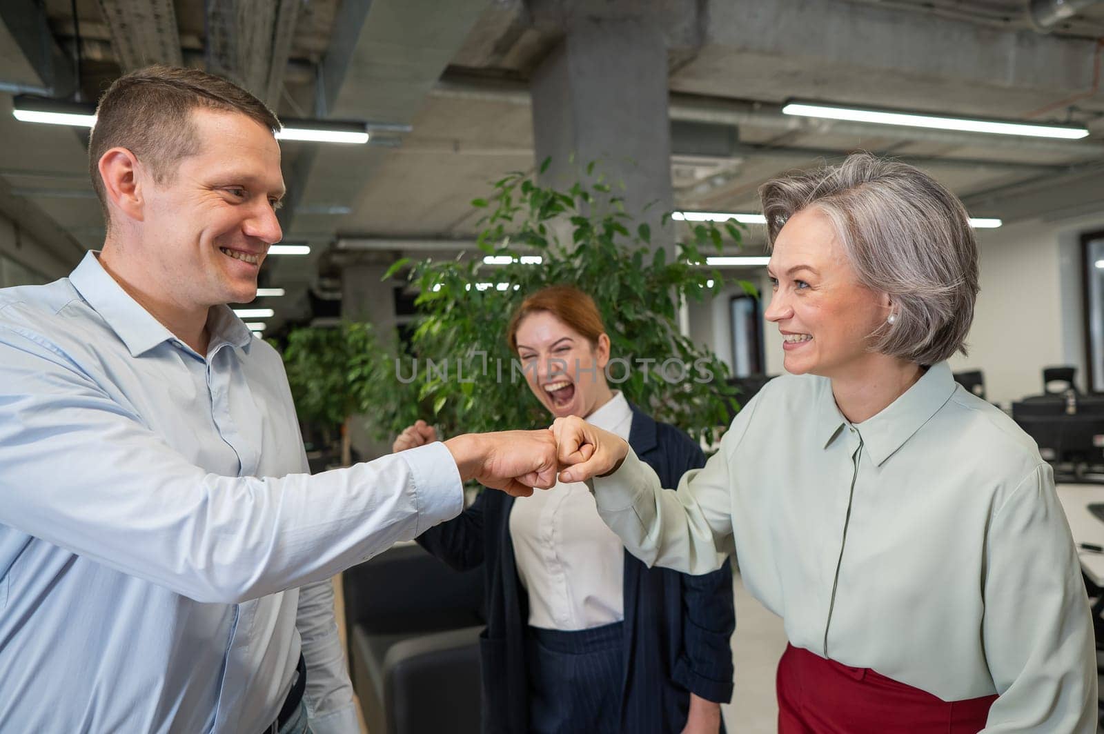 Caucasian man bumping his fists with colleagues as a sign of success