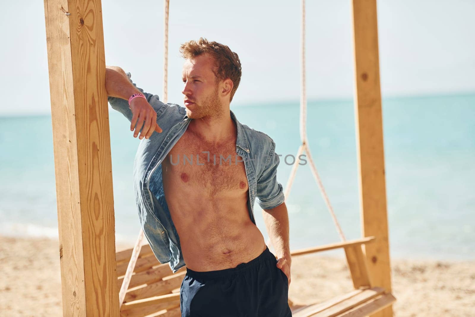 Shows body. Young european man have vacation and enjoying free time on the beach of sea.