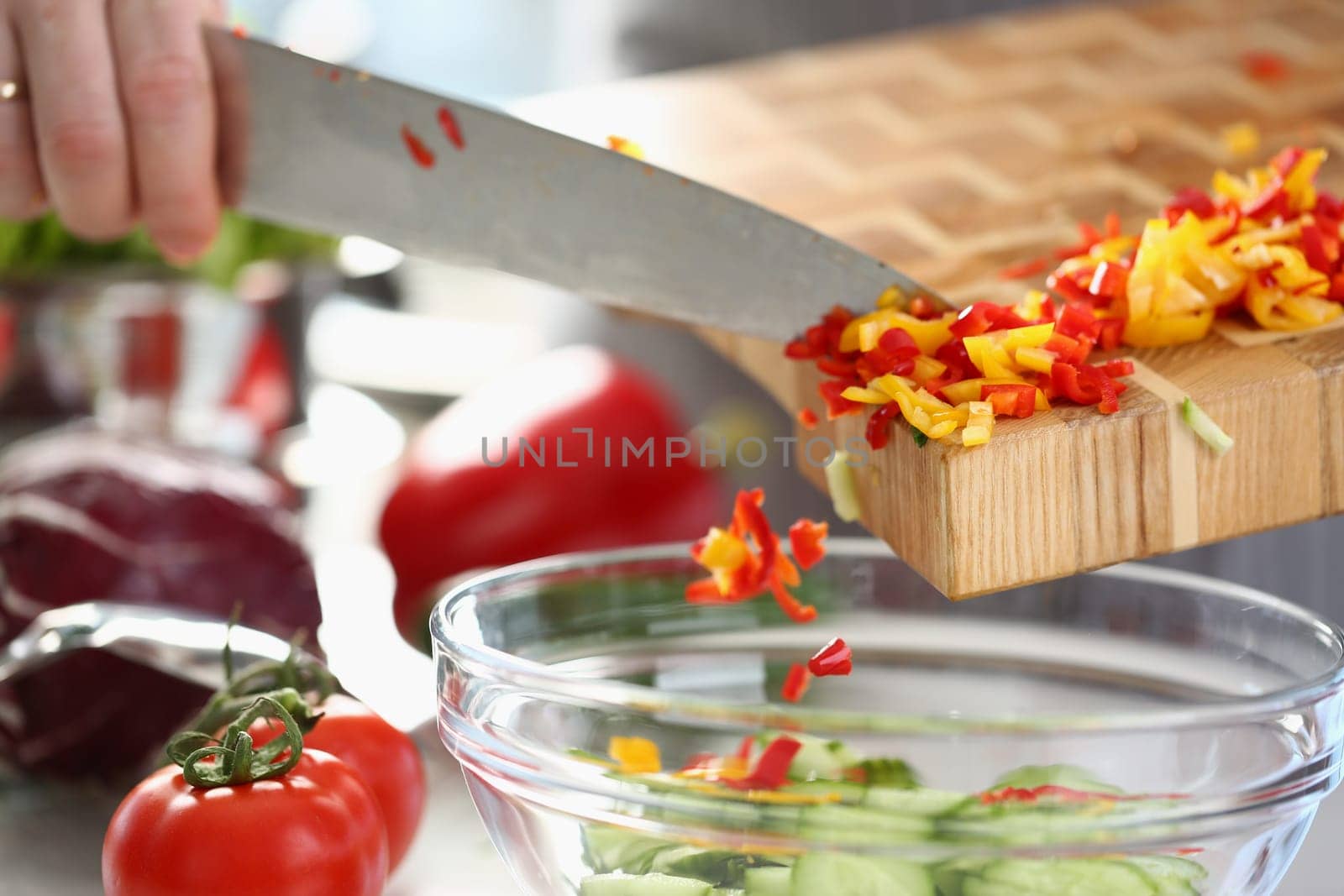 Cook adds chopped red yellow pepper to salad by kuprevich