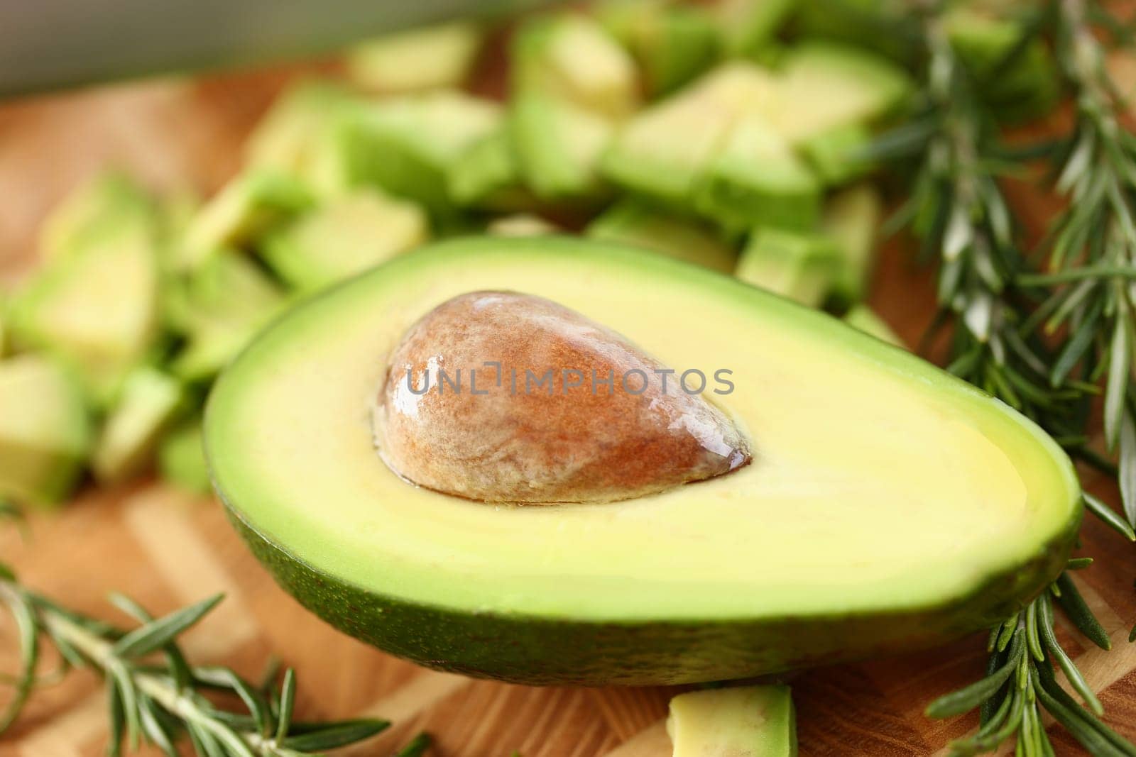 Sliced avocado on cutting board and rosemary. Useful properties of avocado concept