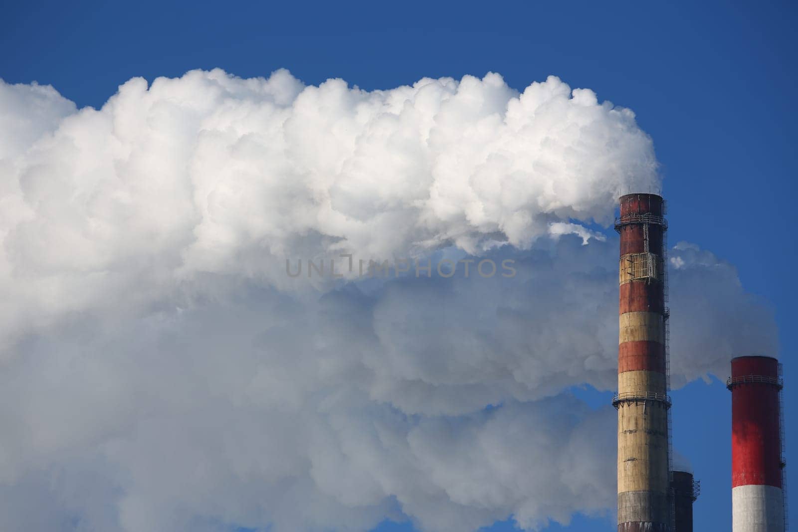 Toxic clouds of smoke come out of factory chimney. CHP and smoking chimneys concept