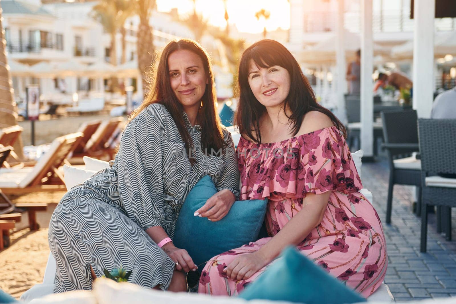 Two female mature friends sitting together outdoors the hotel. Conception of vacation.