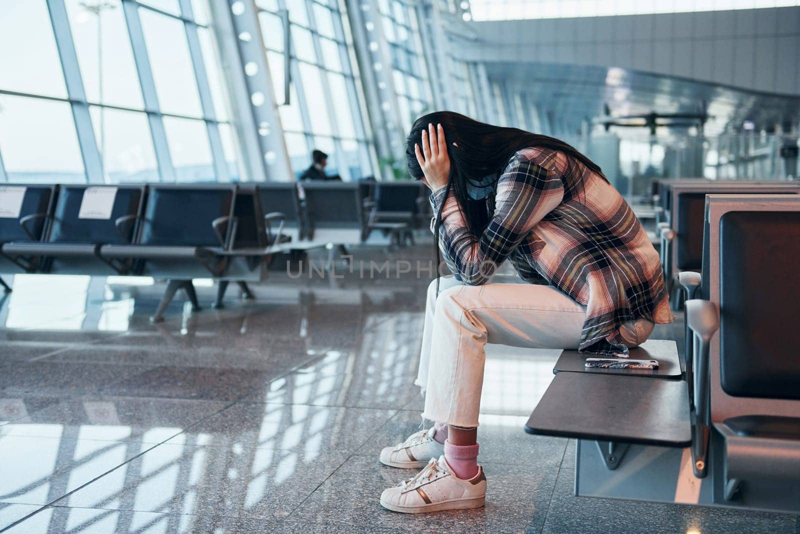 Sad young girl crying when sitting in the modern airport.