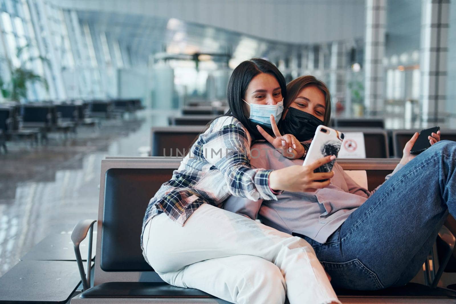 Two happy female friends taking selfie in the modern airport.