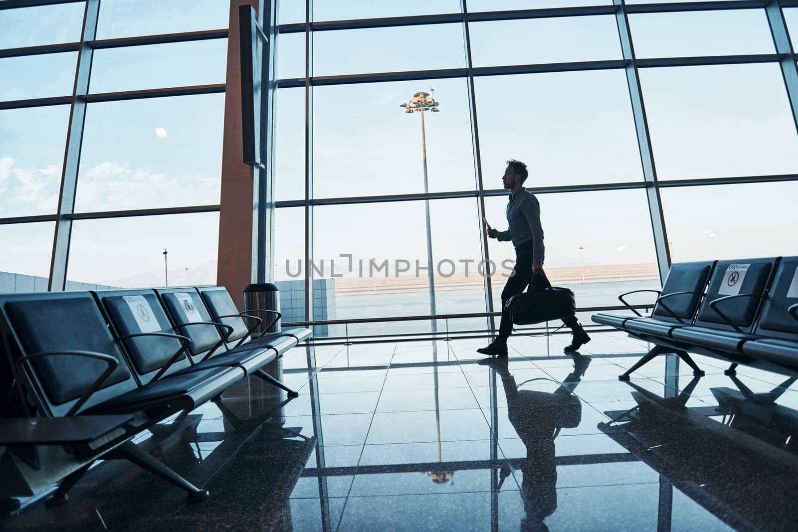 Young man in formal wear is in modern airport. Conception of vacation.