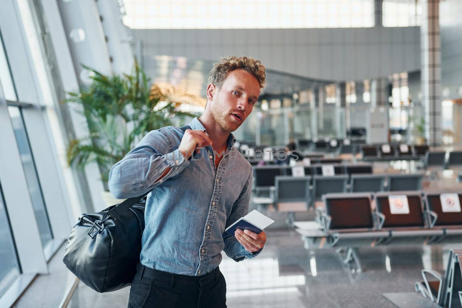 Young man in formal wear is in modern airport. Conception of vacation.