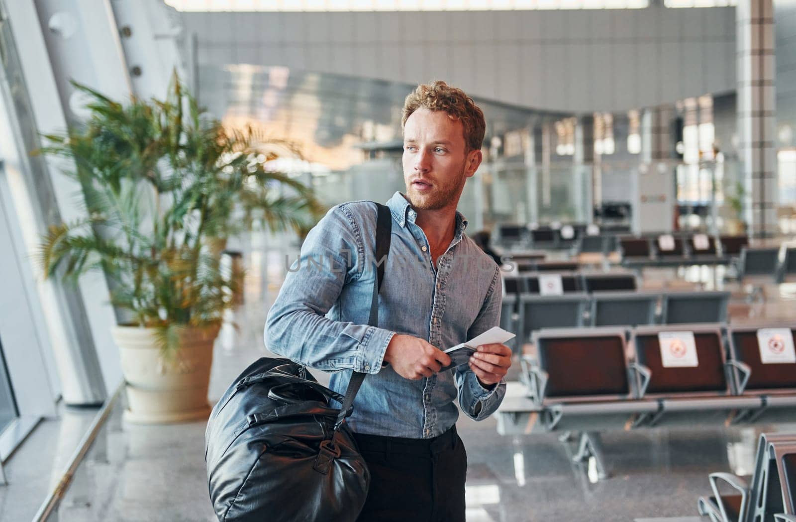 Young man in formal wear is in modern airport. Conception of vacation.
