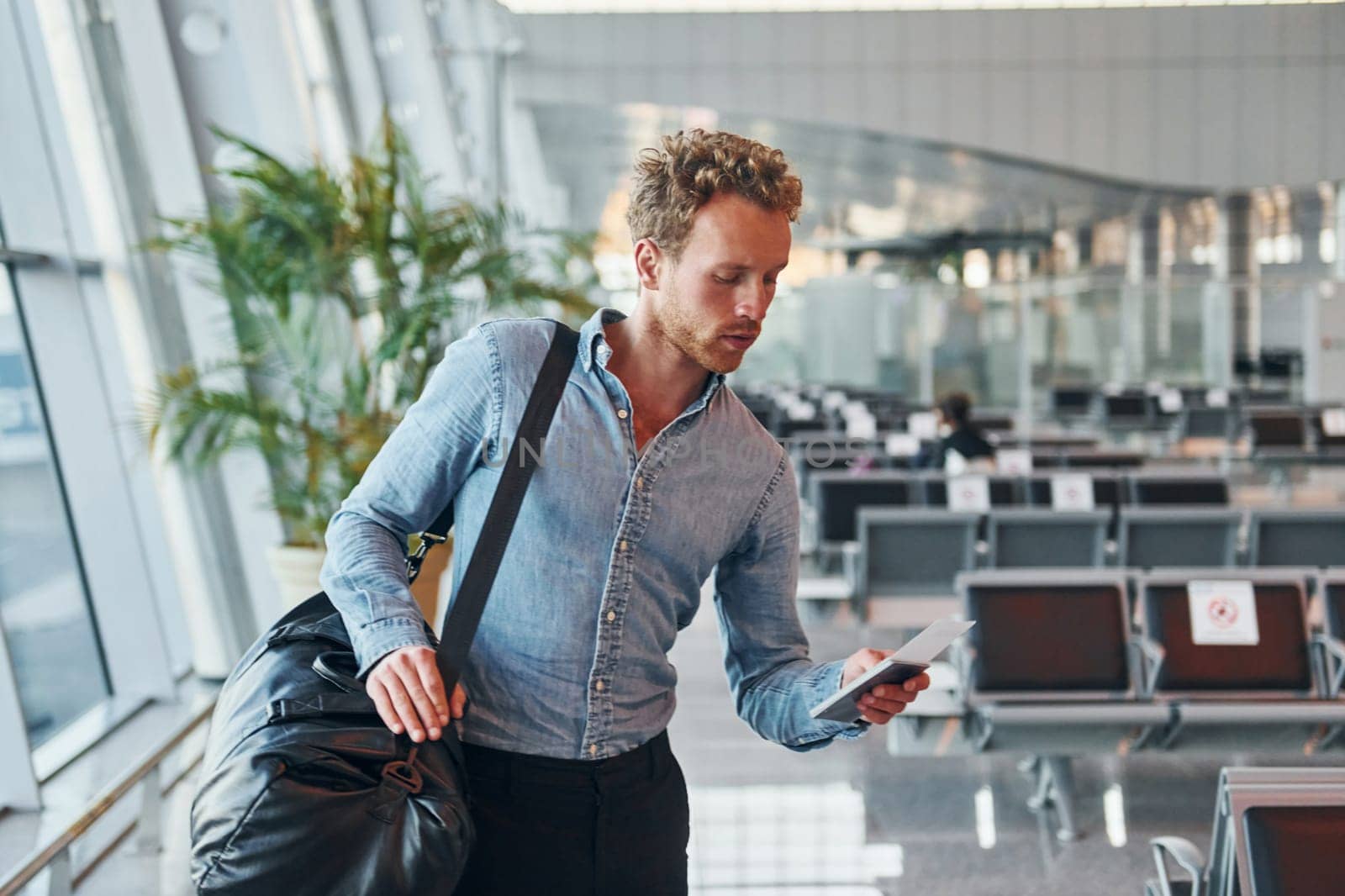 Young man in formal wear is in modern airport. Conception of vacation.