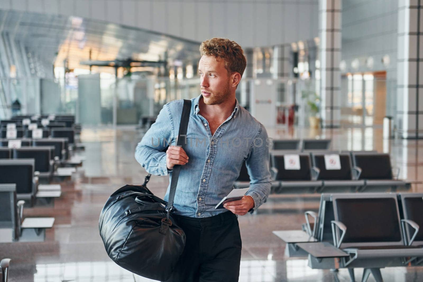 Young man in formal wear is in modern airport. Conception of vacation.