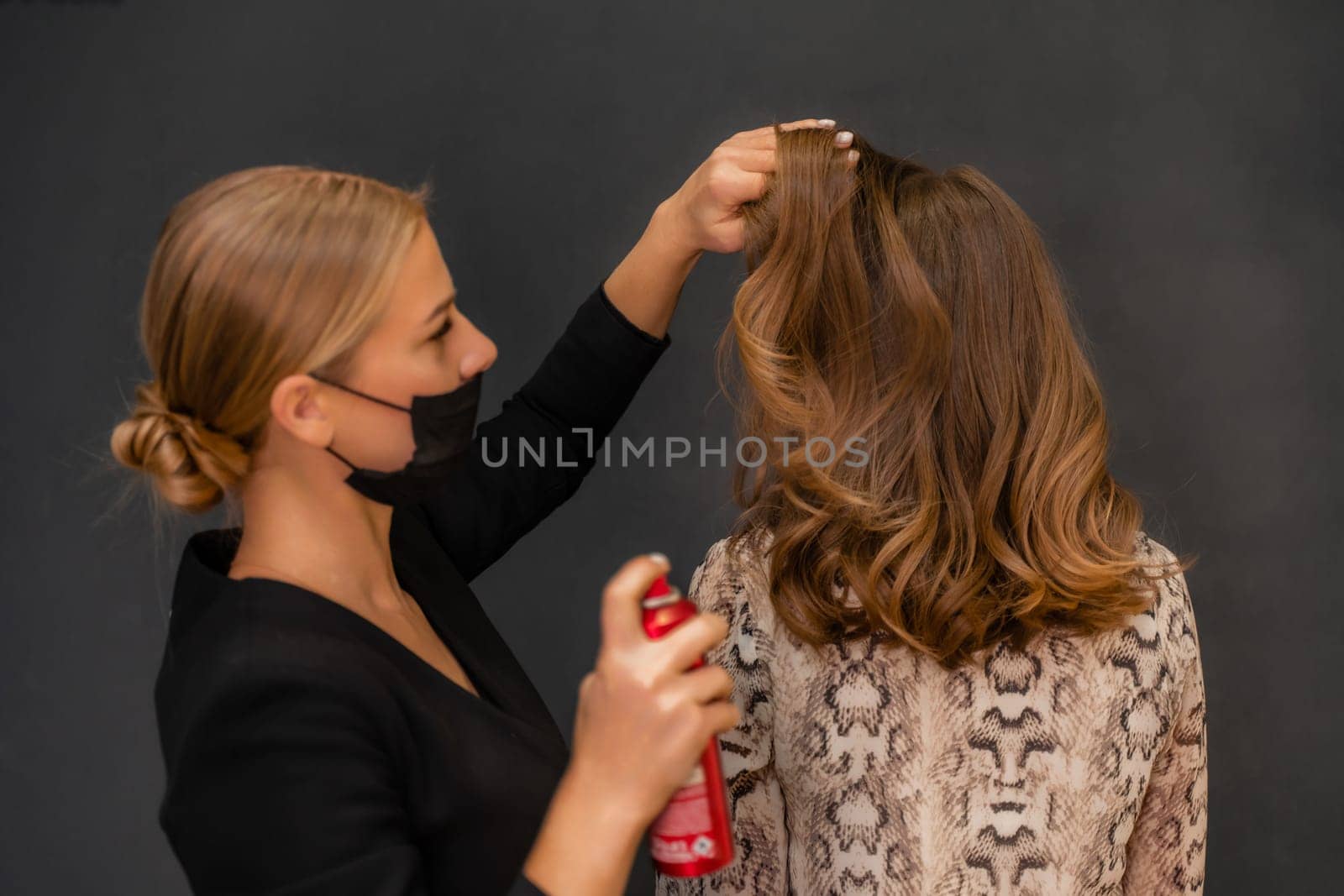 Women salon hairstyle. Hairdresser uses hairspray on client's hair in salon, Portrait of two beautiful women by Matiunina