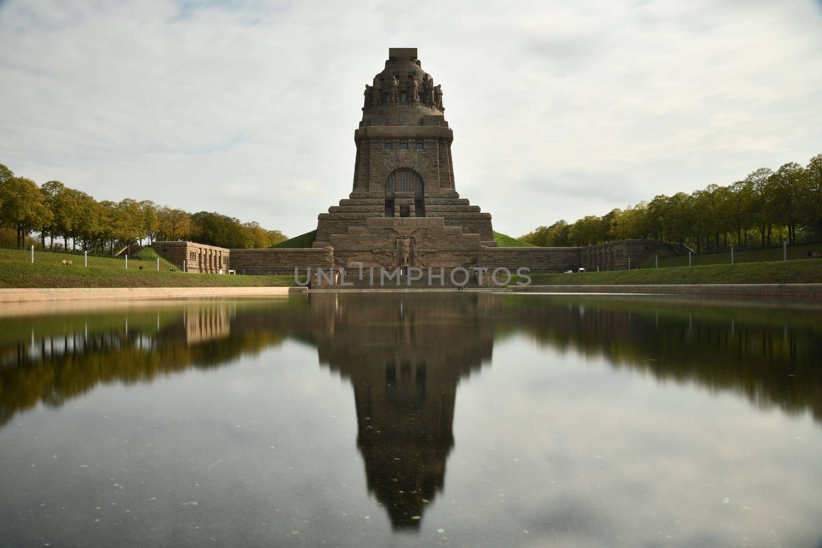 Pond reflecting the Monument to the Battle of the Nations in Leipzig, Germany against a cloudy sky
