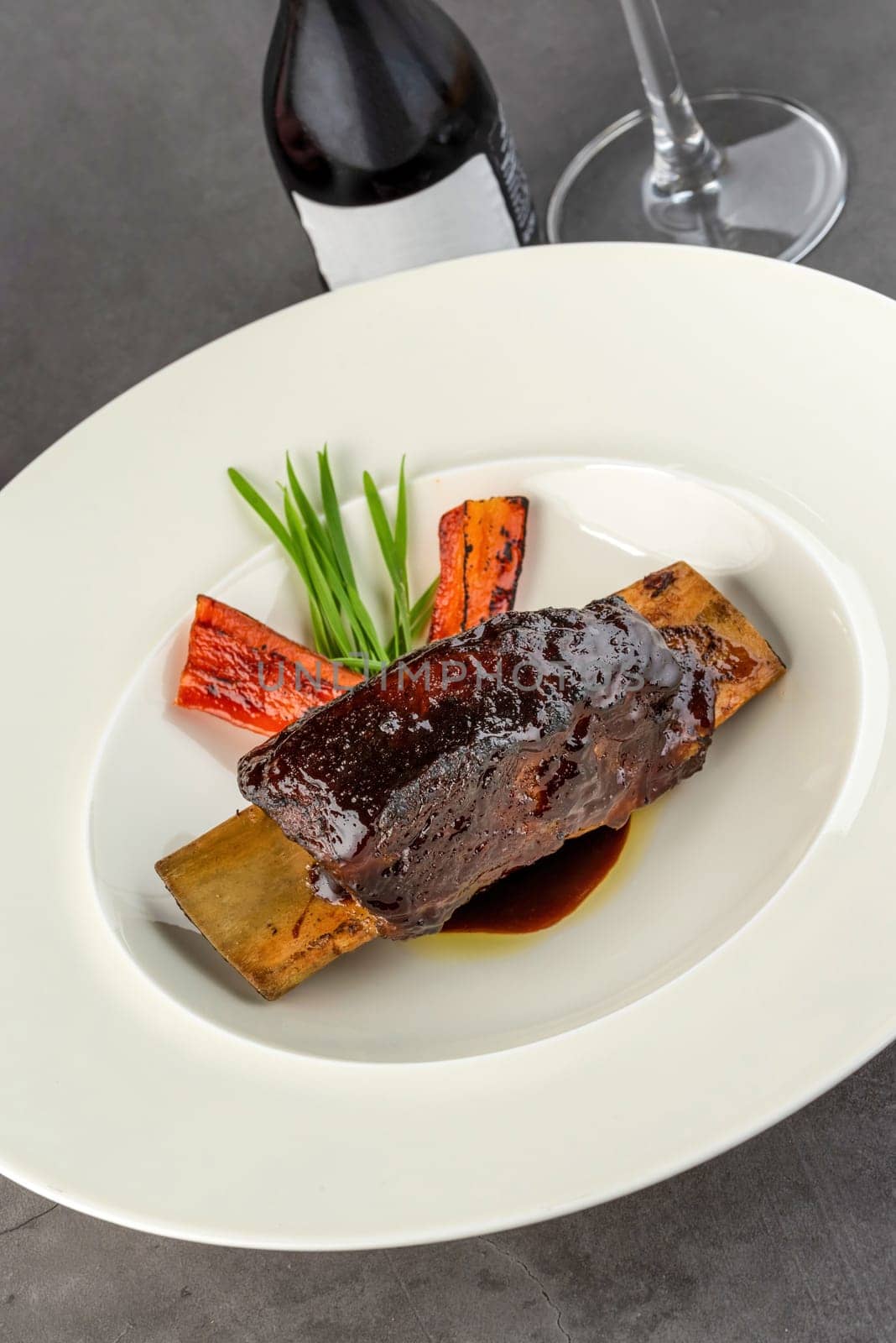 Long cooked marinated beef ribs on a white porcelain plate