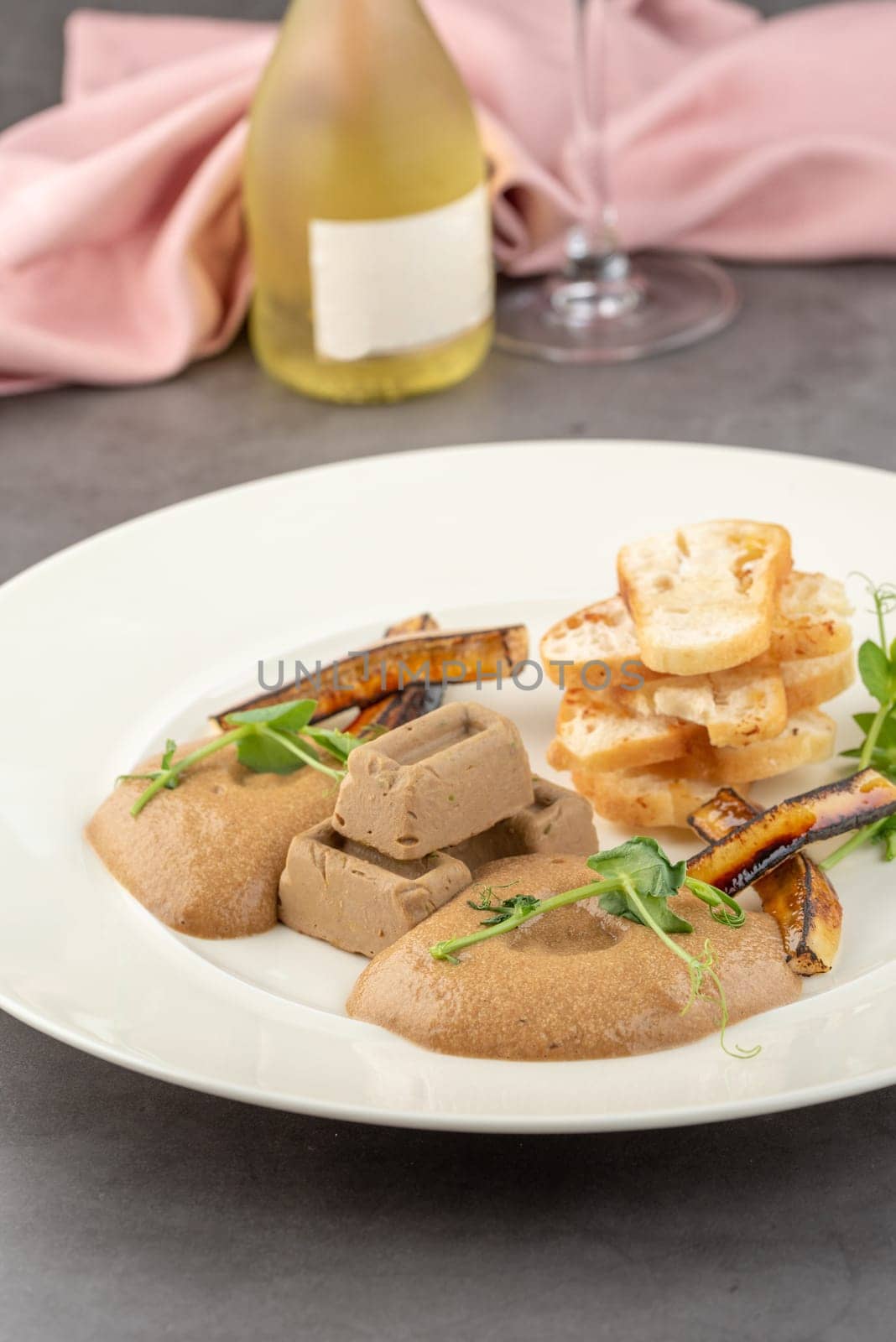 Foie gras with sauce and crispy bread on a white porcelain plate by Sonat