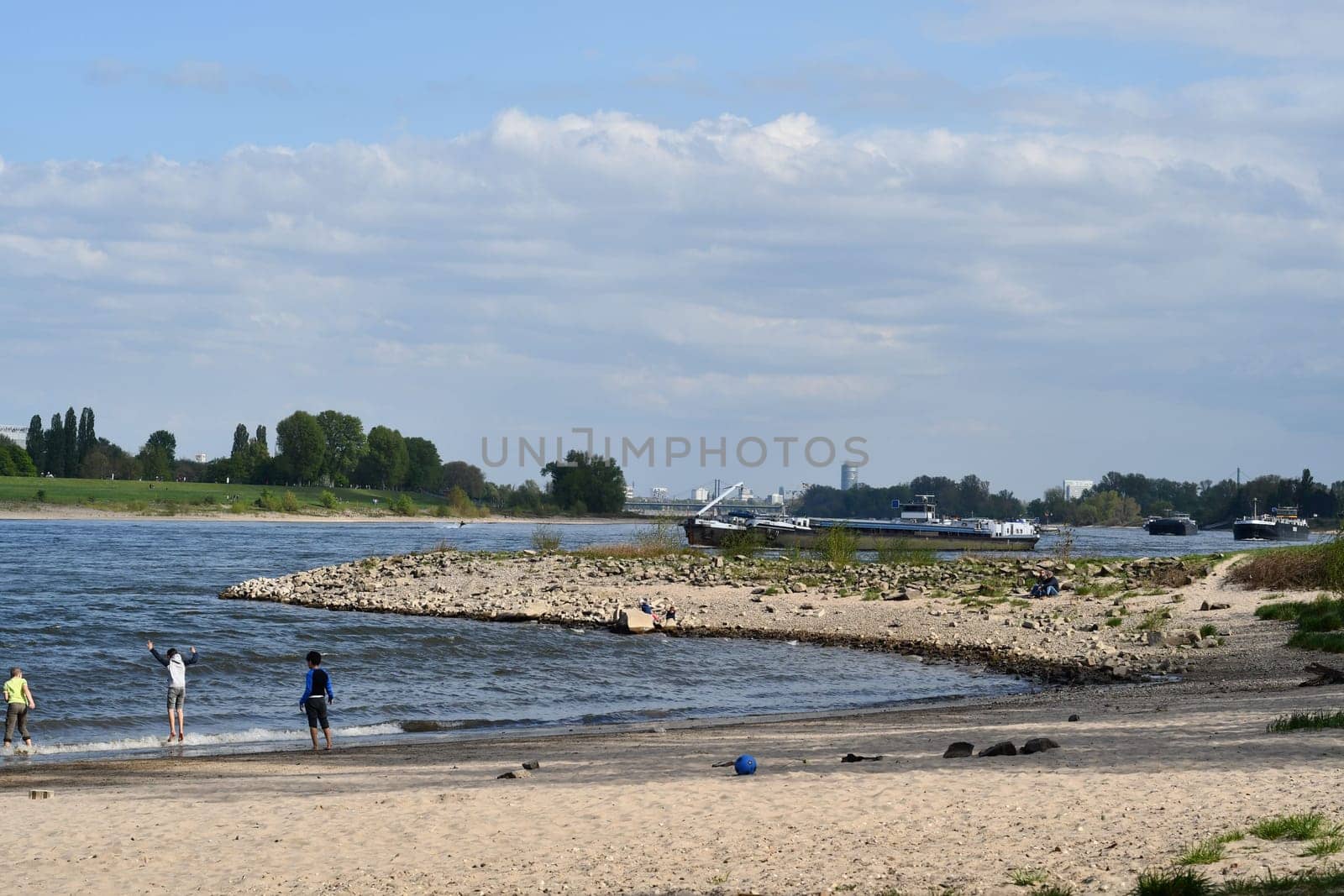 Three children in bathing suits play on the bank of Rhine in Duesseldorf, Germany