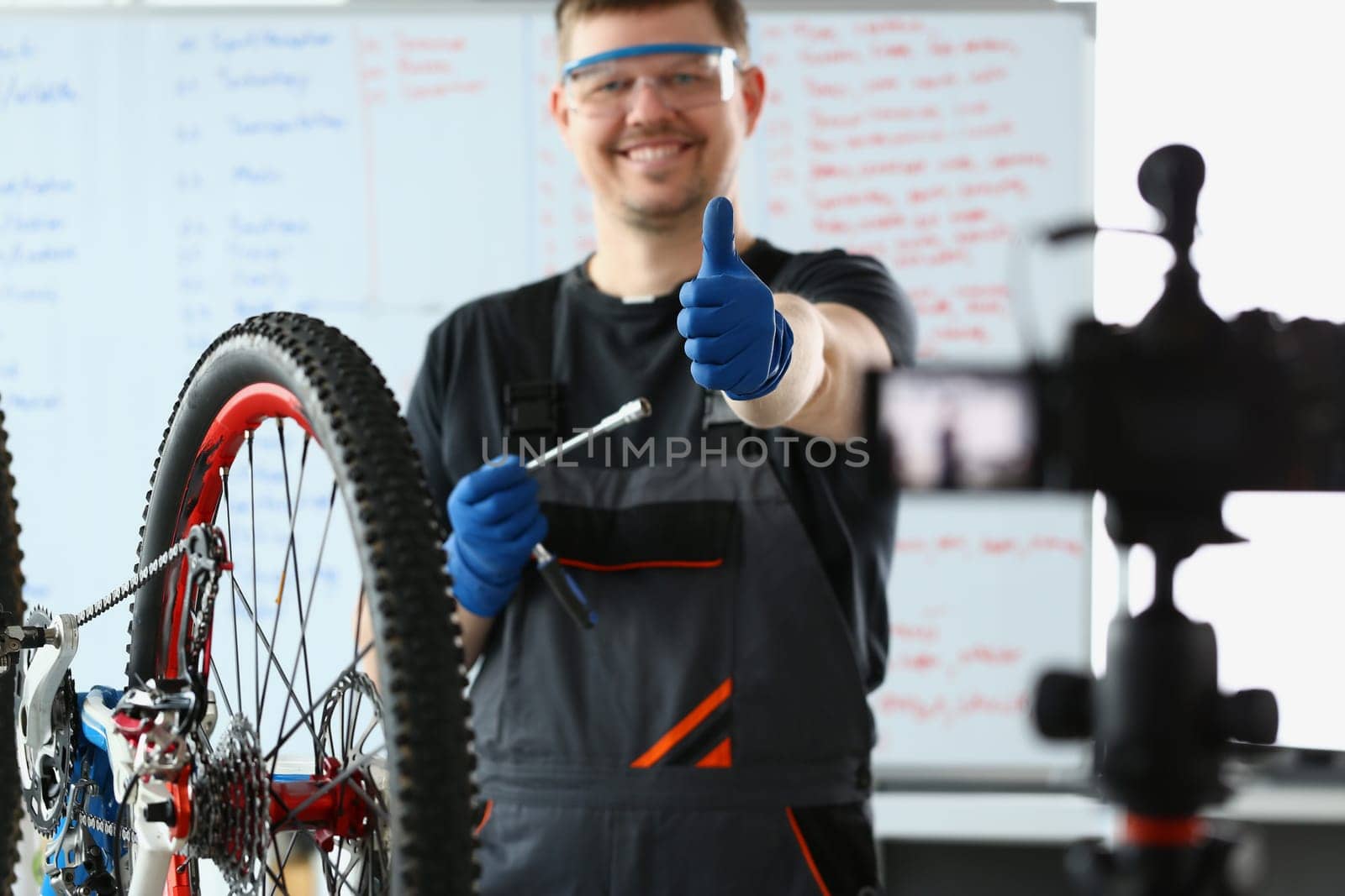 Male blogger holds thumbs up and repairs bicycle remotely by kuprevich